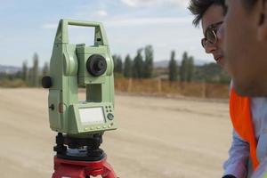 Surveyor engineer is measuring level on construction site. Surveyors ensure precise measurements before undertaking large construction projects. photo