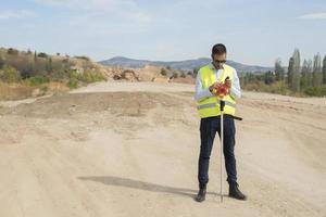 Surveyor engineer is measuring level on construction site. Surveyors ensure precise measurements before undertaking large construction projects. photo