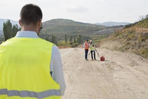 Surveyor engineer is measuring level on construction site. Surveyors ensure precise measurements before undertaking large construction projects. photo