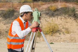 Surveyor engineer is measuring level on construction site. Surveyors ensure precise measurements before undertaking large construction projects. photo