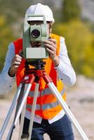 el ingeniero topógrafo está midiendo el nivel en el sitio de construcción. los topógrafos aseguran mediciones precisas antes de emprender grandes proyectos de construcción. foto