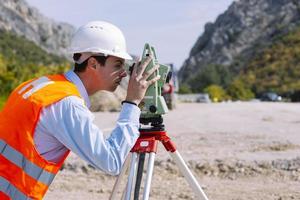 el ingeniero topógrafo está midiendo el nivel en el sitio de construcción. los topógrafos aseguran mediciones precisas antes de emprender grandes proyectos de construcción. foto