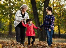 feliz abuela, nieta y nieto jugando en el parque foto