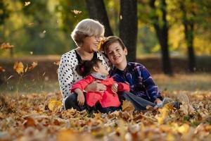 feliz abuela, nieta y nieto jugando en el parque foto