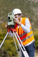 el ingeniero topógrafo está midiendo el nivel en el sitio de construcción. los topógrafos aseguran mediciones precisas antes de emprender grandes proyectos de construcción. foto
