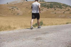 Young man runner running on a mountain road. Jogger training workout in fitness shoe. Healthy lifestyle and sport concept.  Motion blur and selective focus. photo