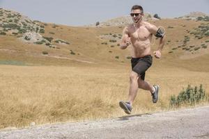 Young man runner running on a mountain road. Jogger training workout in fitness shoe. Healthy lifestyle and sport concept.  Motion blur and selective focus. photo