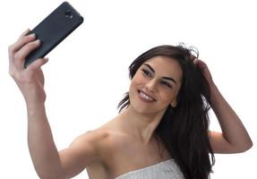 imagen de una hermosa mujer morena riéndose mientras toma una foto selfie en un celular aislado sobre fondo blanco