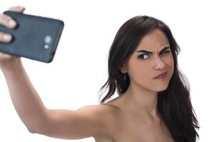 Image of beautiful brunette woman laughing while taking selfie photo on cellphone isolated over white background