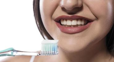 retrato de una atractiva mujer sonriente aislada en un estudio blanco cepillándose los dientes foto