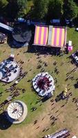 imagens aéreas do parque de diversões, as pessoas estão aproveitando o verão quente em um parque público local da cidade de luton, um parque de diversões foi realizado com passeios assustadores para as famílias. video