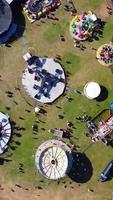 Luftaufnahmen eines Jahrmarkts, die Menschen genießen den heißen Sommer in einem örtlichen öffentlichen Park der Stadt Luton, es wurde ein Jahrmarkt mit gruseligen Fahrgeschäften für Familien abgehalten. video