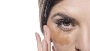 Portrait of a young woman applying liquid make up on her face. Isolated on white background photo