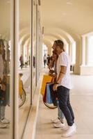 Portrait of cheerful Caucasian young couple man and woman holding many paper bags after shopping while walking and talking on street. Happy family couple with packages outdoor. Buying concept photo