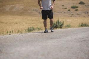 Young man runner running on a mountain road. Jogger training workout in fitness shoe. Healthy lifestyle and sport concept.  Motion blur and selective focus. photo