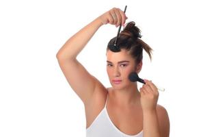 Portrait of a young woman applying make up on her face. Isolated on white background photo