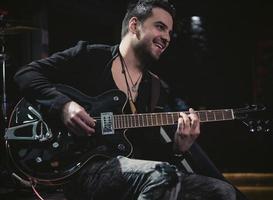 Cerca del hombre tocando la guitarra eléctrica durante el concierto foto