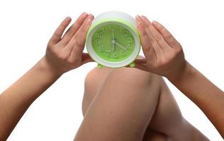 Happy young woman holding clock over isolated white background photo