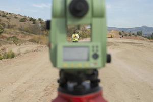 el ingeniero topógrafo está midiendo el nivel en el sitio de construcción. los topógrafos aseguran mediciones precisas antes de emprender grandes proyectos de construcción. foto