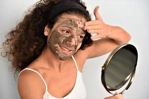 Beautiful woman having clay facial mask photo