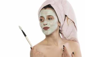 Beautiful woman having clay facial mask apply by beautician. photo