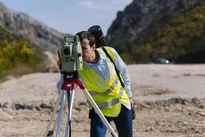 Surveyor engineer is measuring level on construction site. Surveyors ensure precise measurements before undertaking large construction projects. photo