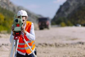 el ingeniero topógrafo está midiendo el nivel en el sitio de construcción. los topógrafos aseguran mediciones precisas antes de emprender grandes proyectos de construcción. foto