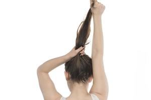 modelo femenino arreglando su cabello. mujer atando el cabello en un moño. foto