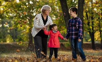 feliz abuela, nieta y nieto jugando en el parque foto