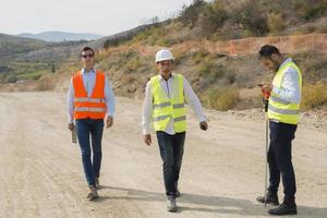 Team of young engineer and architects working, meeting, discussing, designing, planning, measuring layout of blueprints in construction site photo