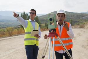 el ingeniero topógrafo está midiendo el nivel en el sitio de construcción. los topógrafos aseguran mediciones precisas antes de emprender grandes proyectos de construcción. foto