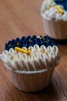 Luxurious and elegant cupcakes, with white cream and navy blue with gold sprinkles. photo