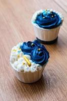 Luxurious and elegant cupcakes, with white cream and navy blue with gold sprinkles. photo