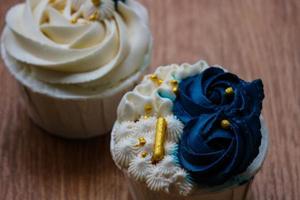 Luxurious and elegant cupcakes, with white cream and navy blue with gold sprinkles. photo