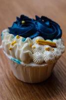 Luxurious and elegant cupcakes, with white cream and navy blue with gold sprinkles. photo