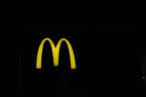 West Java, Indonesia on July 2022. Glowing McDonalds restaurant sign against night sky. Logo of Mcd Drive Thru. photo