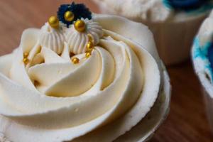 Luxurious and elegant cupcakes, with white cream and navy blue with gold sprinkles. photo