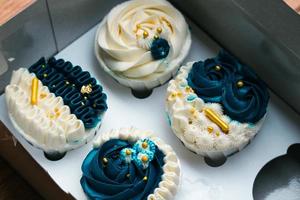 Luxurious and elegant cupcakes, with white cream and navy blue with gold sprinkles. photo