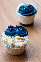 Luxurious and elegant cupcakes, with white cream and navy blue with gold sprinkles. photo