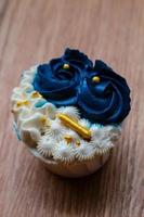 Luxurious and elegant cupcakes, with white cream and navy blue with gold sprinkles. photo