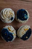 Luxurious and elegant cupcakes, with white cream and navy blue with gold sprinkles. photo