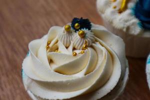 Luxurious and elegant cupcakes, with white cream and navy blue with gold sprinkles. photo