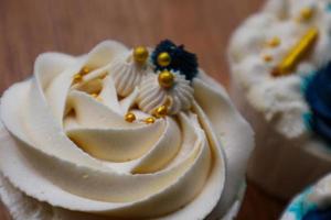 Luxurious and elegant cupcakes, with white cream and navy blue with gold sprinkles. photo