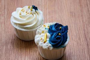 cupcakes lujosos y elegantes, con crema blanca y azul marino con chispas doradas. foto