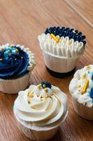 Luxurious and elegant cupcakes, with white cream and navy blue with gold sprinkles. photo