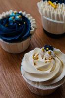 Luxurious and elegant cupcakes, with white cream and navy blue with gold sprinkles. photo