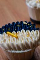 Luxurious and elegant cupcakes, with white cream and navy blue with gold sprinkles. photo