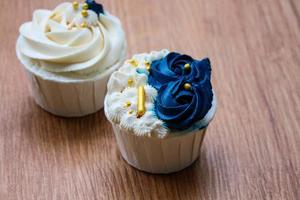 Luxurious and elegant cupcakes, with white cream and navy blue with gold sprinkles. photo