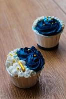 Luxurious and elegant cupcakes, with white cream and navy blue with gold sprinkles. photo