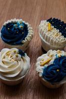 Luxurious and elegant cupcakes, with white cream and navy blue with gold sprinkles. photo